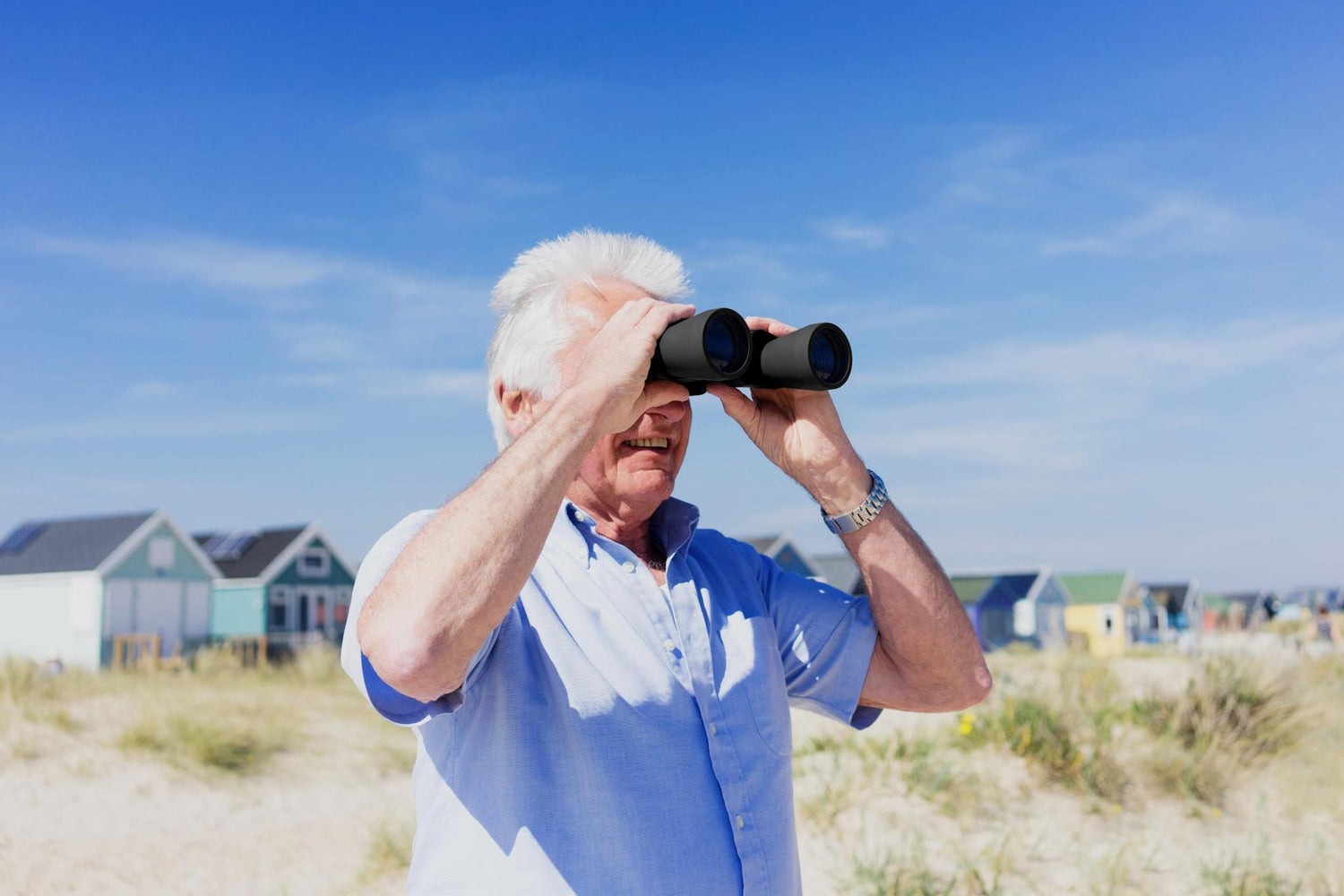 Retired gentleman spotting boats on the beach with Praktica binoculars.